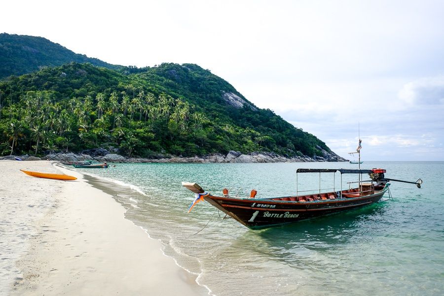 Bottle Beach (Haad Khuat), Koh Phangan A longtail boat named Bottle Beach moored on the sand below jungle hills, Koh Phangan, Thailand