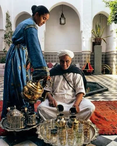A Dada pouring Moroccan mint tea in a riad courtyard