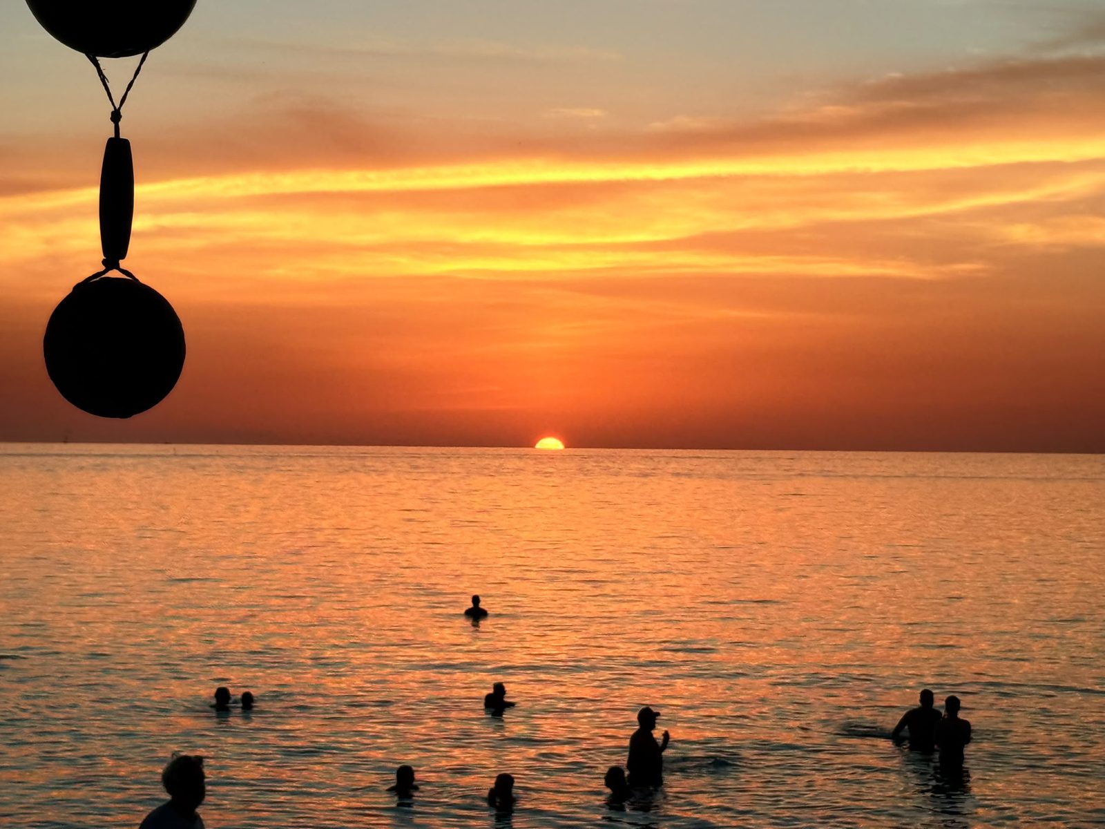 Swimmers in the sea as the sun sets over Zen Beach beside Grasshopper Beach Bar, Koh Phangan