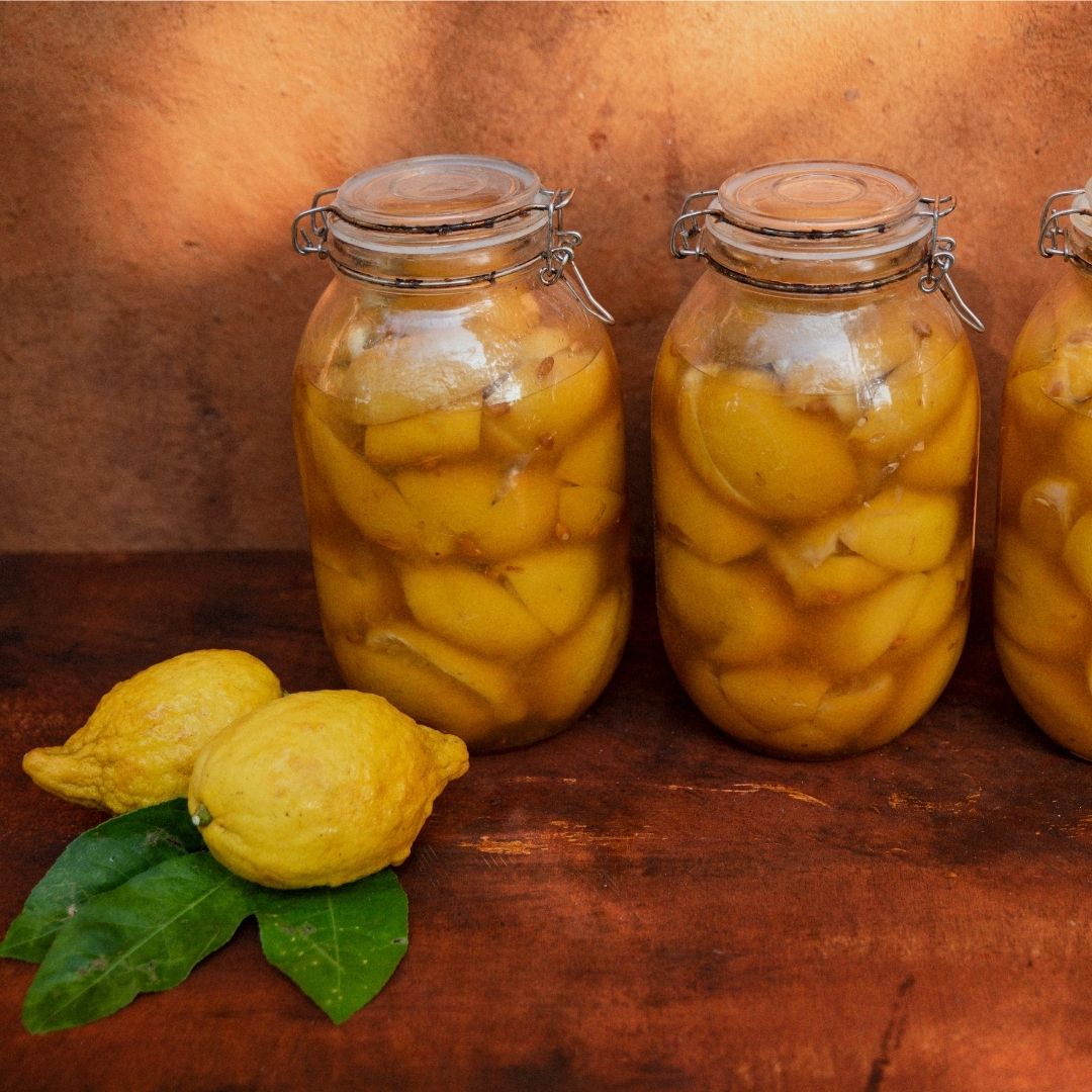 Jars of Moroccan preserved lemons with fresh lemons